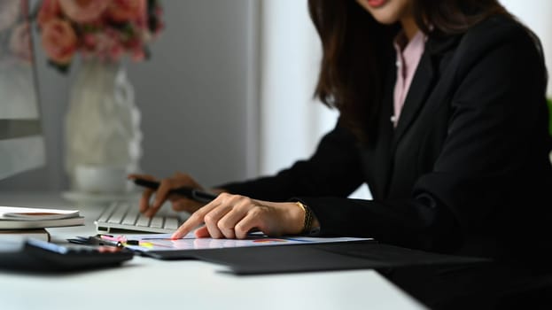 Professional female analyst working with graph and statistic document on office desk.