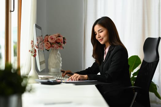 Attractive female economist working with graph and statistic document on office desk.