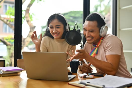 Cheerful young woman and biracial transgender man recording podcast from home studio. Radio, podcasts and blogging.