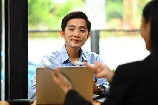 Asian male employee working on new business strategy with colleagues at office.