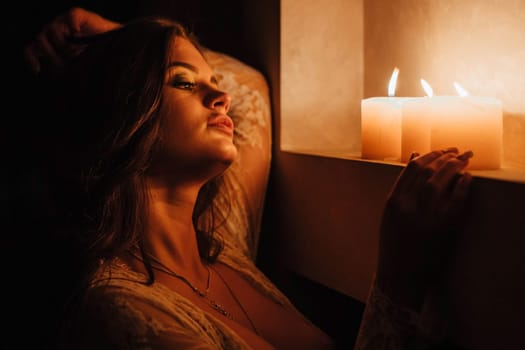 Aromatherapy. A sexy brunette in underwear extinguishes candles before bedtime. Romantic setting on Valentine's Day.