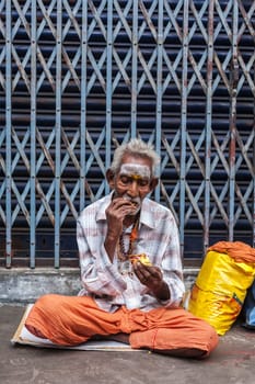 TIRUCHIRAPALLI, INDIA - FEBRUARY 14, 2013: Unidentified old Indian man eating in the street