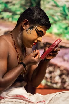 KOCHI, INDIA - FEBRUARY 24, 2013: Unidentified Kathakali exponent preparing for performance by applying face make-up. Kathakali is the classical dance form of Kerala