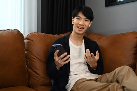 Asian man talking with mobile phone in living room..