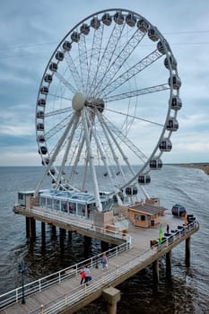 The Hague, Netherlands - May 13, 2017: The Scheveningen Pier Strandweg, beach resort on North sea in The Hague Den Haag with Ferris wheel. The Hague, Netherlands