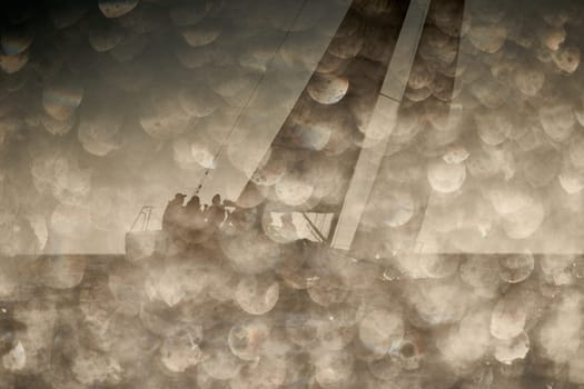The view through the spray of how the sailboat is heeling at sunset, boat roll, splashes shine in the sun, sailors on the board. High quality photo