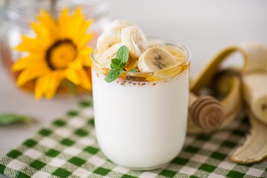 Sweet homemade yogurt with bananas and honey in a glass