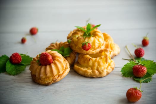 Cooked sweet curd cupcakes with fresh strawberries and mint on a wooden table.
