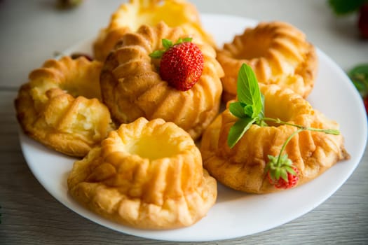 Cooked sweet curd cupcakes with fresh strawberries and mint on a wooden table.
