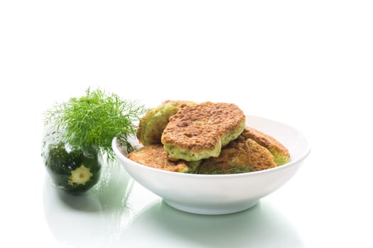 fried zucchini pancakes with herbs, in a plate isolated on a white background.