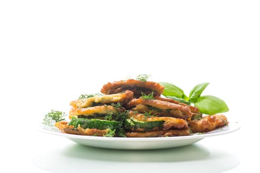 zucchini fried in circles in batter with herbs, in a plate isolated on a white background.