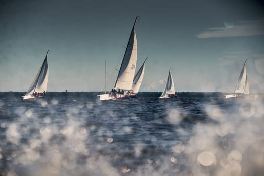 Russia, St.Petersburg, 07 July 2023: The sailing race, few boats in a roll go at high speed, sailing boats are in regatta at sunset, handsome sailors on the board of yacht, wind and splashes. High quality photo