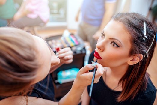 Close-up of a make-up artist contouring red lips to model.  