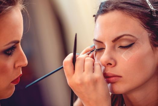 Close-up of a make-up artist applying the eyeliner to a model.