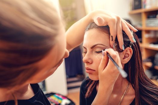 Make-up artist applying the eyeliner to model. Close-up. 