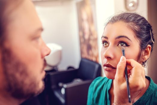 Close-up of a makeup man artist getting eyeshadow to a model.