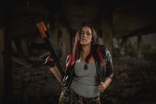 Young beautiful military woman holding rifle.