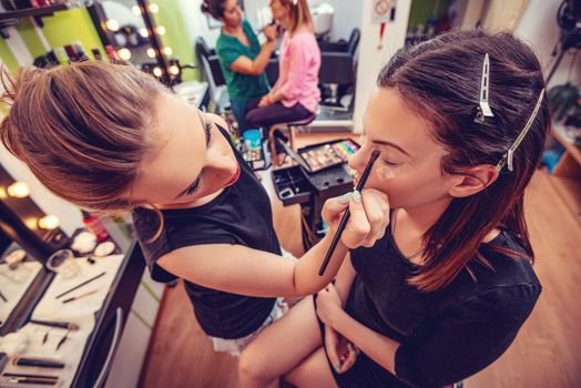 Make-up artist applying the eyeshadow to model. 