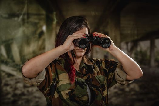 Young woman wearing a camouflage uniform, looking through binoculars.