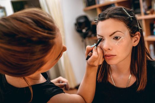 A pretty woman having makeup applied by a makeup artist.