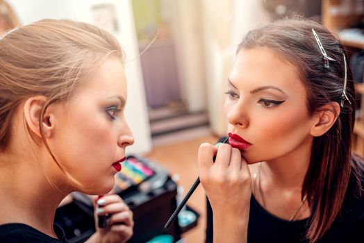 Make-up artist contouring lips to model.  