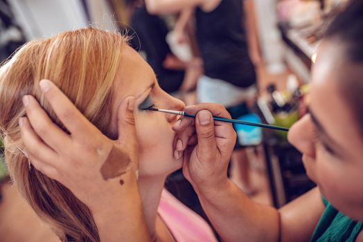 Make-up artist applying the eyeliner to model. Close-up. 