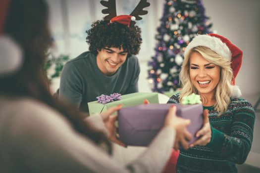 Happy best friends on a background of New Year's decor open Christmas presents. Selective focus.