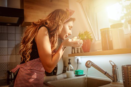 Beautiful young woman washing vegetables and prepares  cauliflower for cooking while standing in the kitchen. 