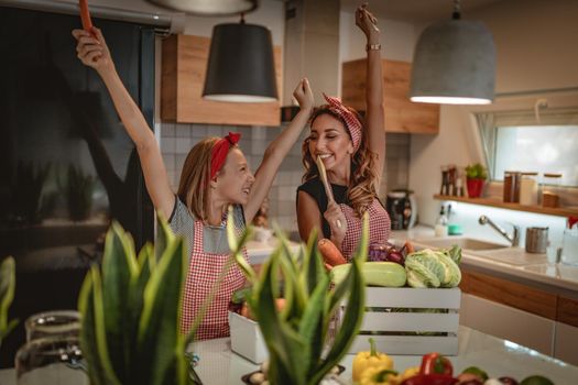 Happy mother and her daughter enjoy and having fun in making and having healthy meal together at their home kitchen.
