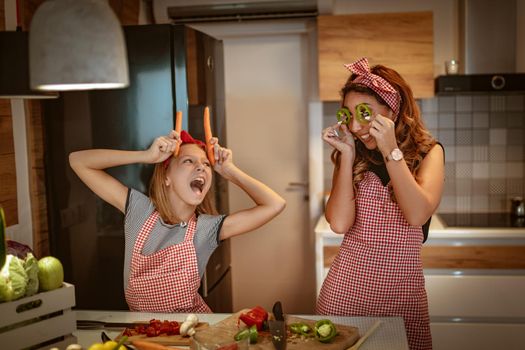 Happy mother and her daughter enjoy and having fun in making and having healthy meal together at their home kitchen.