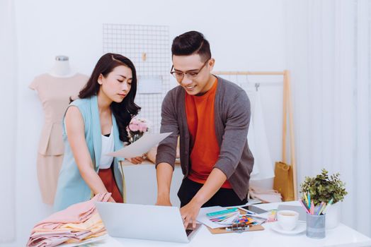 Young woman and man fashion designer using laptop to search for new ideas