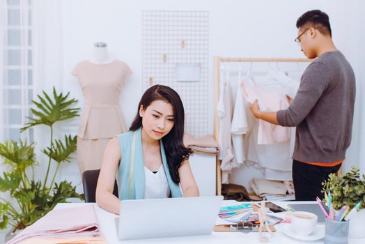 Fashion designers at work.  Handsome male designer choosing design while his colleague working with laptop.