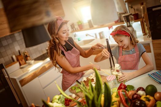 Happy mother and her daughter enjoy preparing for marinating cauliflower and making healthy meal together at their home kitchen.  