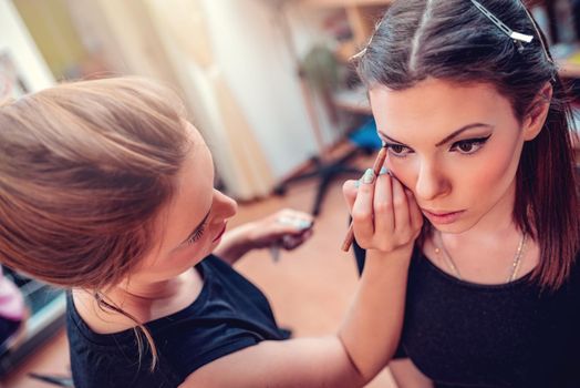 Make-up artist applying the eyeliner to model. 