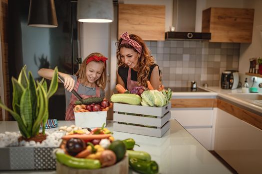 Happy mother and her daughter enjoy making and having healthy meal together at their home kitchen.