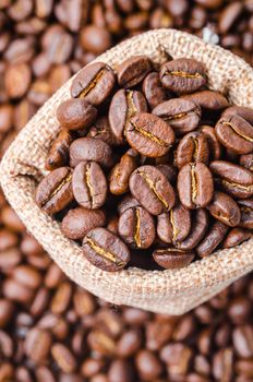 Coffee beans in sack bag on coffee beans background.