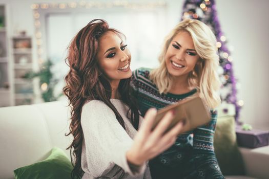 Three cheerful best friends having nice time in an apartment and taking a selfie. Selective focus. 