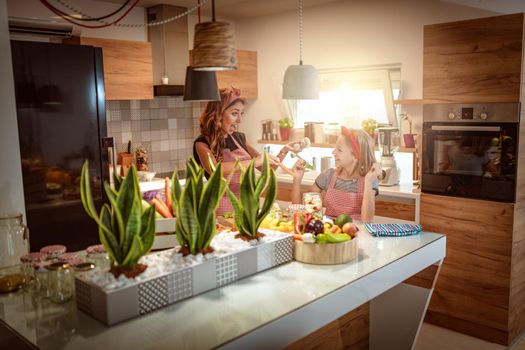 Happy mother and her daughter enjoy preparing for marinating cauliflower and making healthy meal together at their home kitchen.  