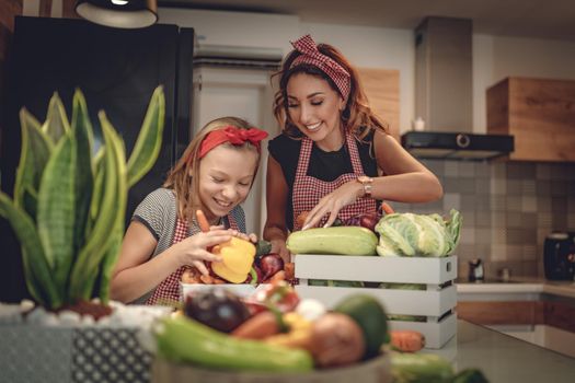 Happy mother and her daughter enjoy making and having healthy meal together at their home kitchen.