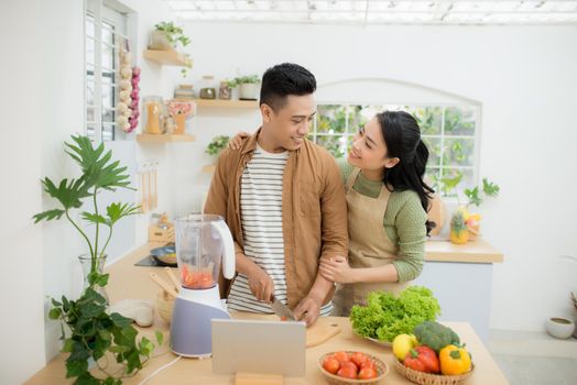 Portrait of a pretty young couple cooking together according to a recipe on a tablet computer