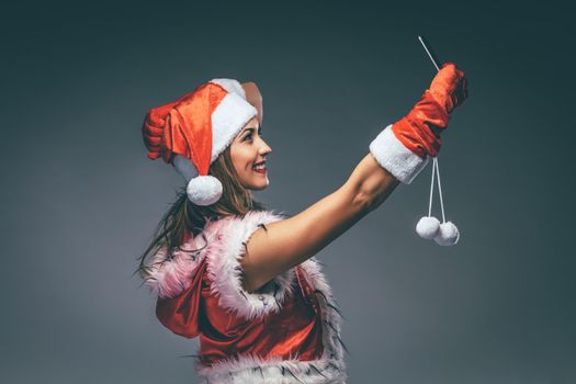 Beautiful young smiling woman in Santa Claus costume taking a selfie with smartphone. 