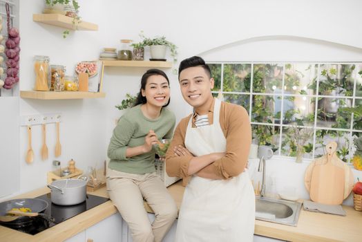 Happy young couple eating and talking in the kitchen