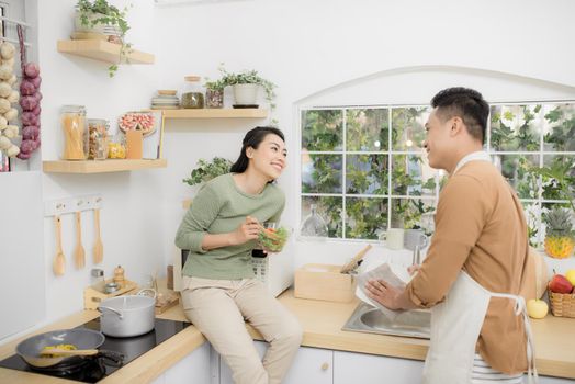 Happy young couple eating and talking in the kitchen