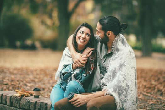 Beautiful smiling couple enjoying in sunny city park in autumn colors looking each other.