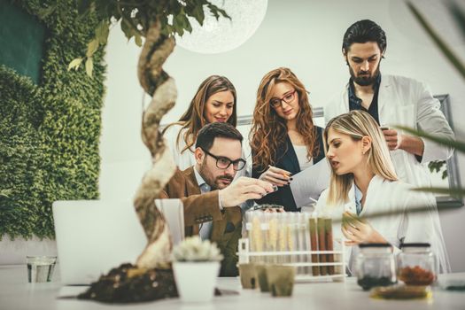 University colleague biologists taking experiment on sprout and checking the analysis of the sample of plant.