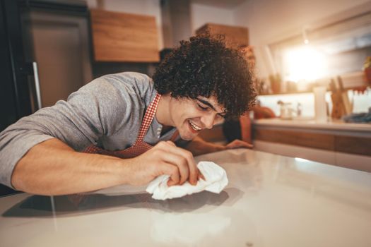 Young couple is prepared dinner, and a man is cleaning the table after mixing dough and the woman is washing dishes.