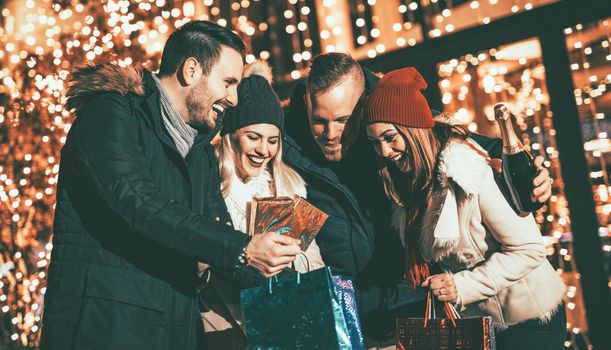 Happy beautiful young couples holding gifts they bought, while standing in mall and checking their shopping bags.