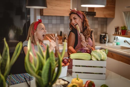 Happy mother and her daughter enjoy and having fun in making and having healthy meal together at their home kitchen.