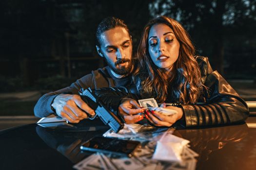 Dangerous criminal man is holding a gun and counting the money with his girlfriend after criminal job done.