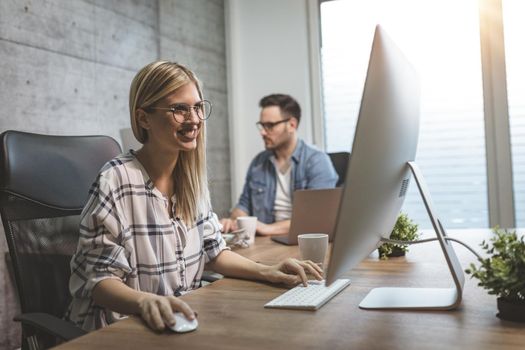 Young beautiful successful smiling business woman working on computer in the office.